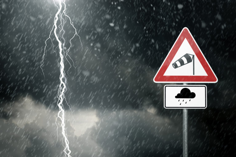 Ein Foto von schlechtem Wetter und Blitzen mit einem Schild das vor Sturm und Regen warnt